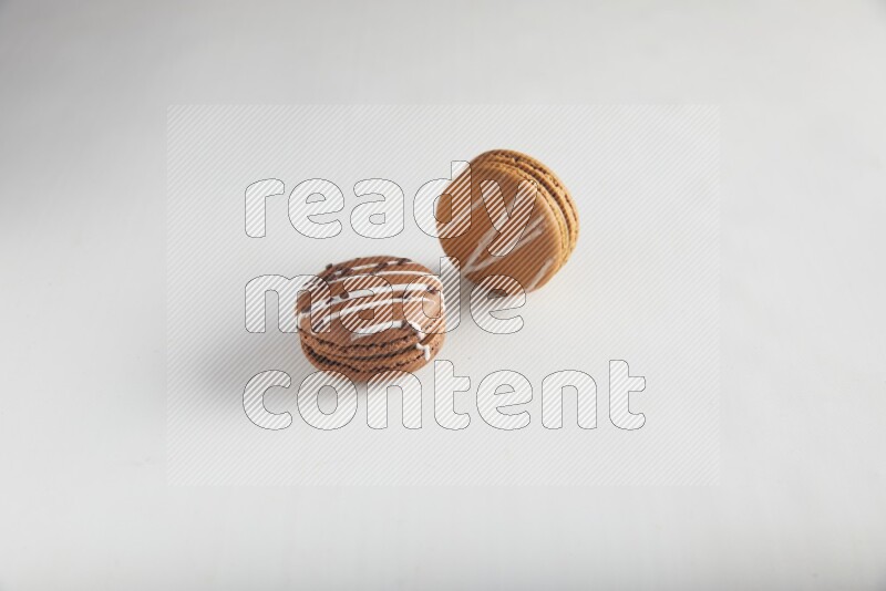 45º Shot of of two assorted Brown Irish Cream, and Brown white Chocolate Caramel macarons on white background