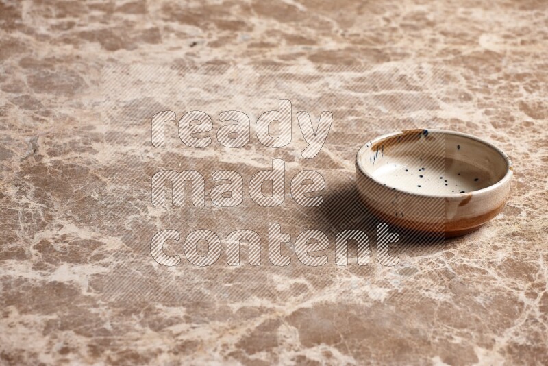 A multicolored pottery plate on beige marble background