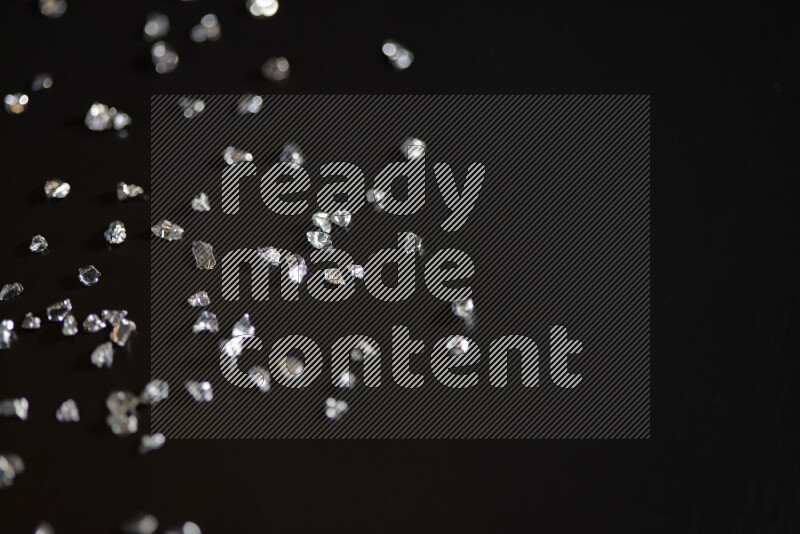 Silver shimmering fragments of glass scattered on a black background