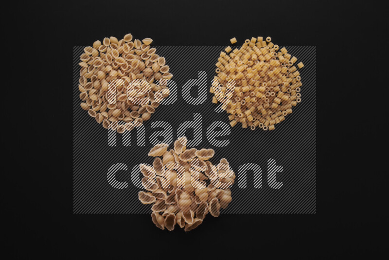 Different pasta types in bunches on black background