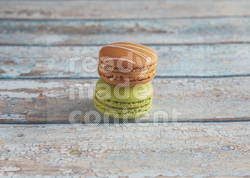 45º Shot of of two assorted Brown Irish Cream, and Green Pistachio macarons  on light blue background