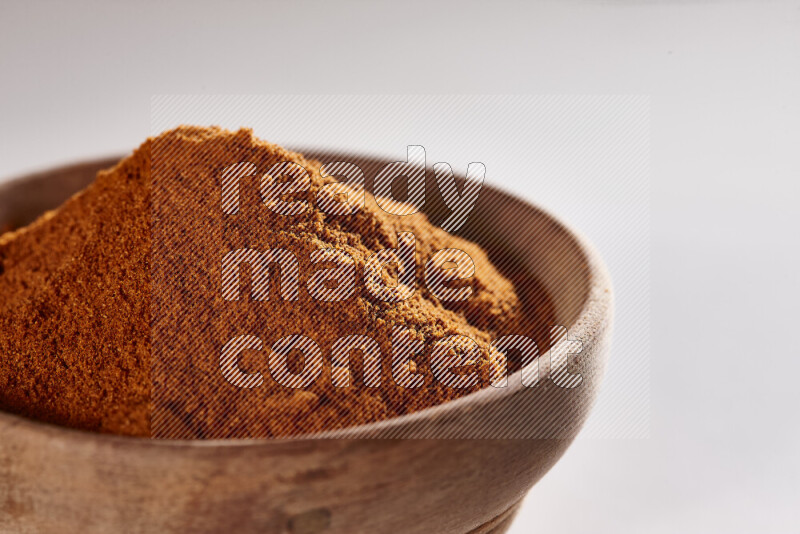 A wooden bowl full of ground paprika powder on white background