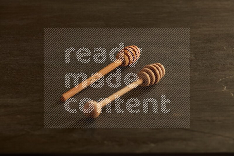 Wooden honey dipper on black slate background