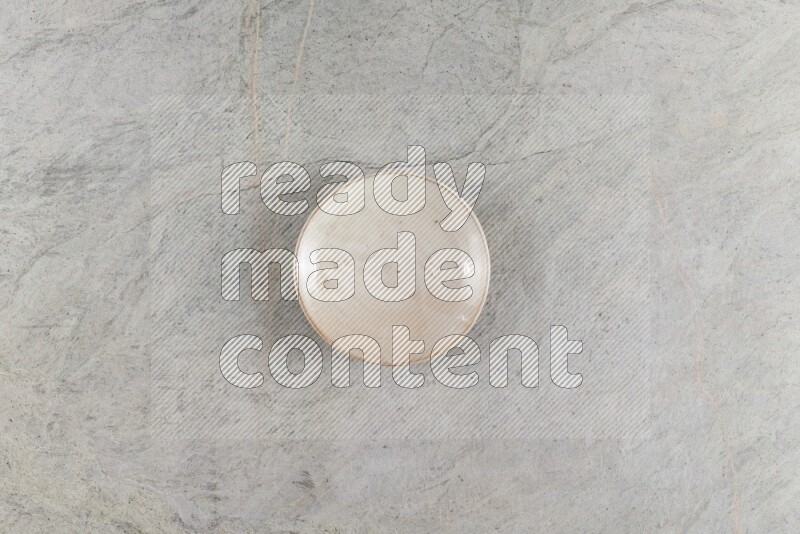 A beige pottery plate on grey marble background