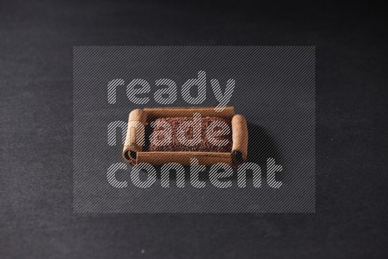 A single square of cinnamon sticks full of garden cress on black flooring