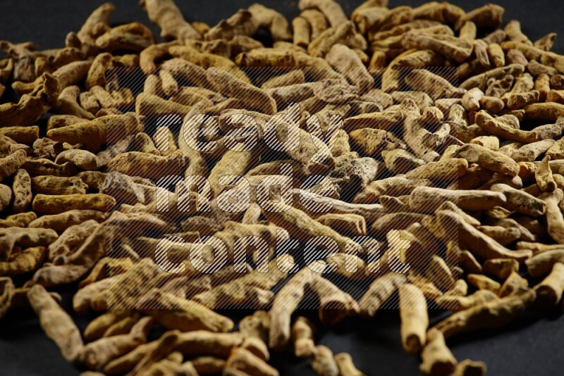 Dried turmeric fingers on black flooring