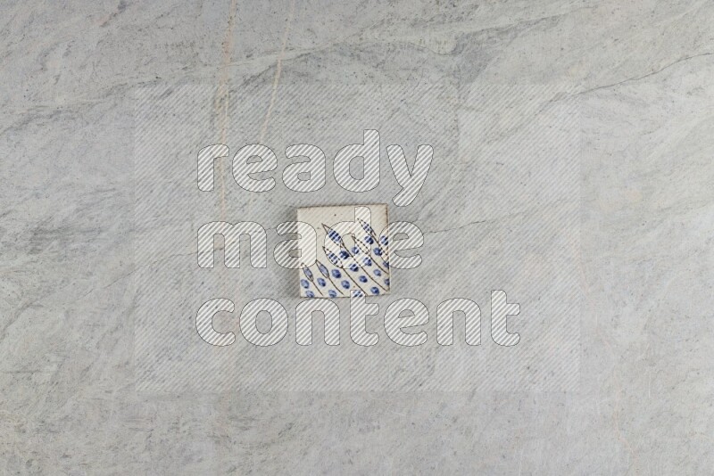A decorative pottery coaster on grey marble background