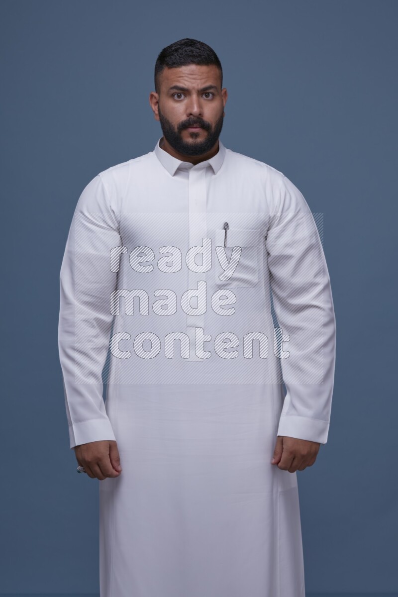 A man Posing in Blue Background wearing a Saudi Thob