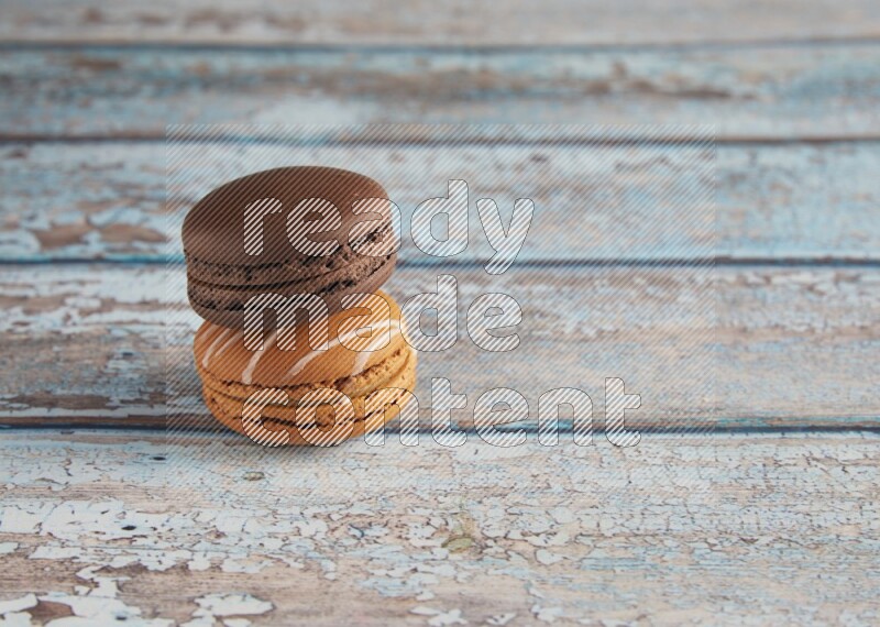 45º Shot of of two assorted Brown Irish Cream, and Brown Dark Chocolate macarons on light blue background