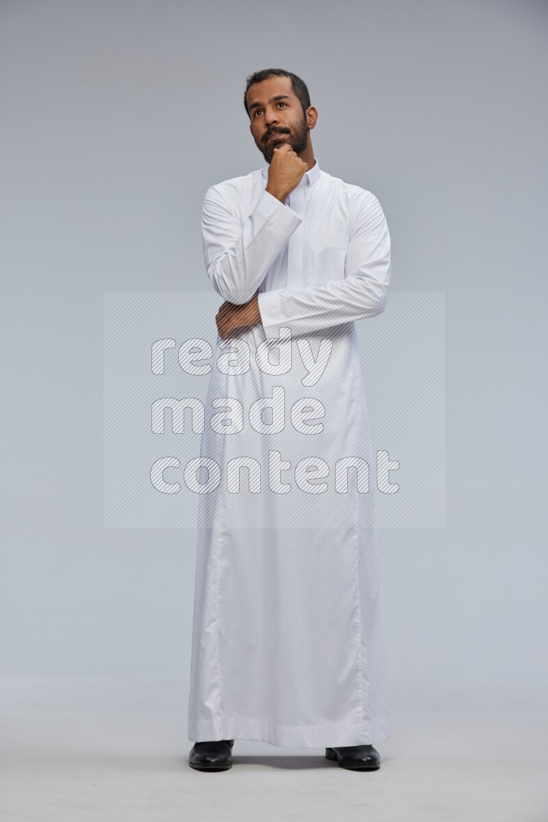 Saudi man Wearing Thob standing interacting with the camera on Gray background