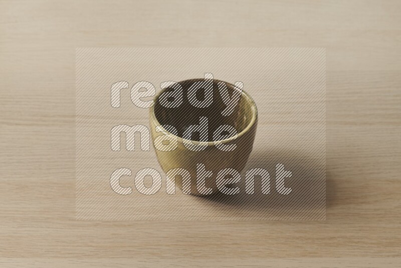 A multicolored pottery cup on light wooden background