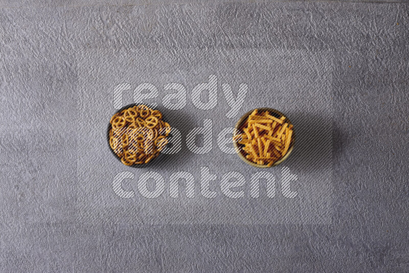 Assorted snacks in pottery bowls on grey background