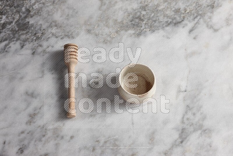 Multicolored pottery bowl with wooden honey dipper on the side on grey marble background