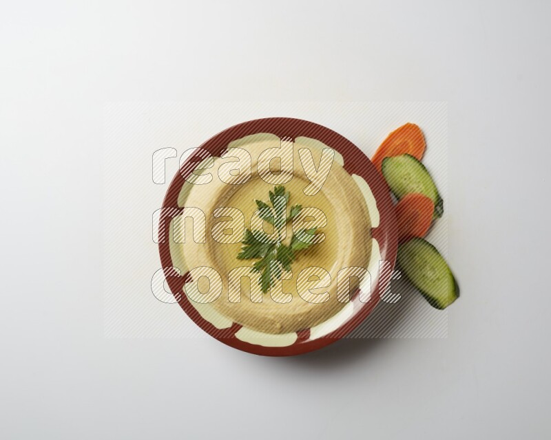 Hummus in a traditional plate garnished with parsley on a white background