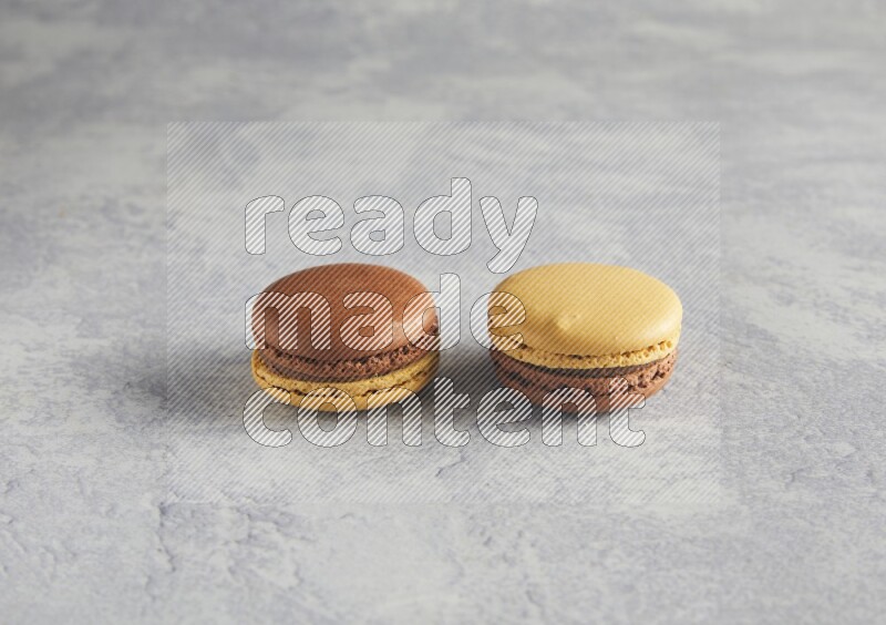 45º Shot of two Yellow and Brown Chai Latte macarons r on white  marble background