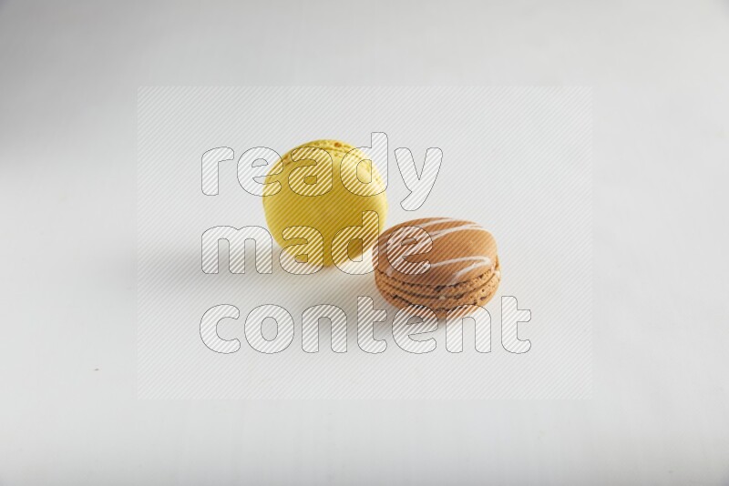 45º Shot of of two assorted Brown Irish Cream, and Yellow Lemon macarons on white background