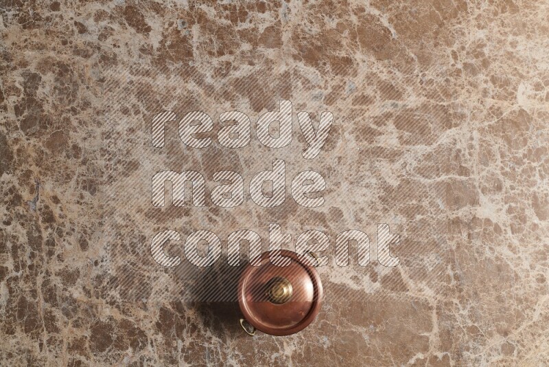 A small copper pot on beige marble background