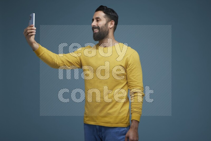 Man Taking a Selfie  in a blue background wearing a yellow shirt