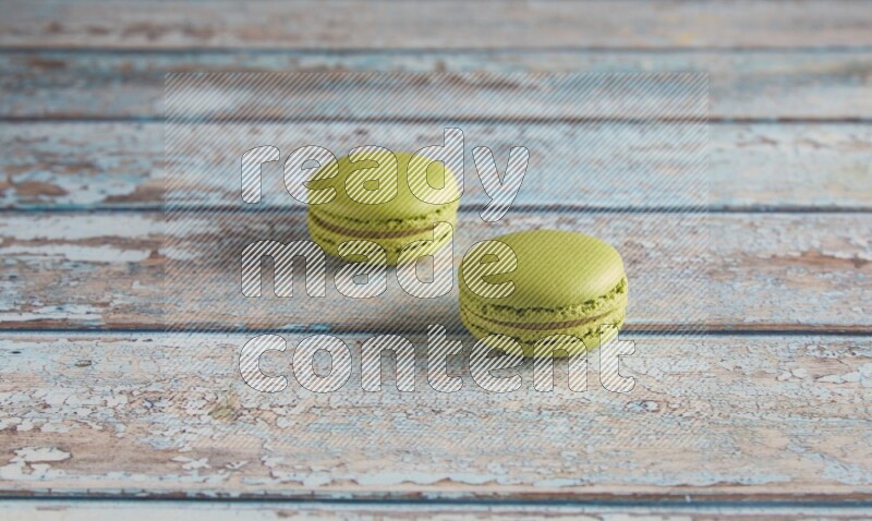 45º Shot of two Green Pistachio macarons on light blue wooden background