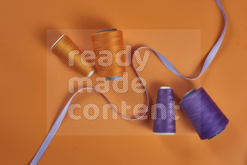 A purple collection of sewing and tailoring tools arranged on a orange background