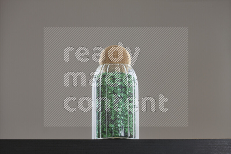 Sequins in a glass jar on black background