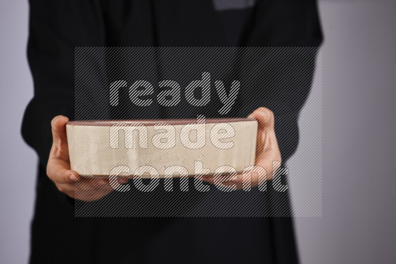 A woman in black abaya holding different pottery essentials in different positions
