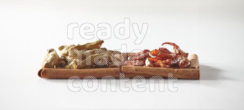 2 squares of cinnamon sticks full of dried red chilis and turmeric fingers on white flooring