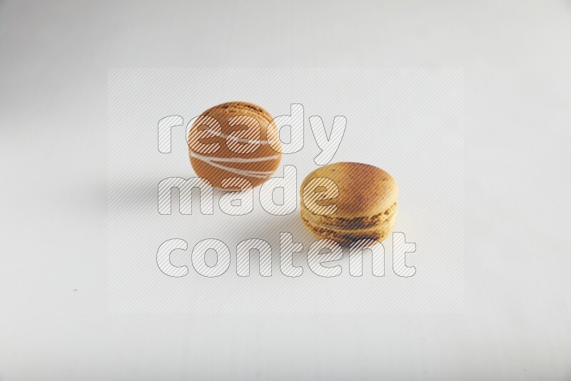 45º Shot of of two assorted Brown Irish Cream, and Yellow Crème Brulée macarons on white background