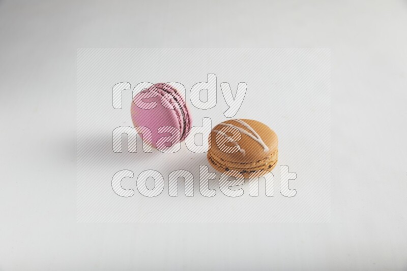 45º Shot of of two assorted Brown Irish Cream, and Purple Strawberry macarons on white background