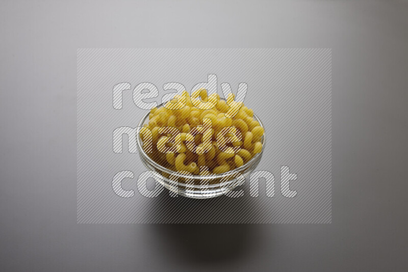 Twist pasta in a glass bowl on grey background