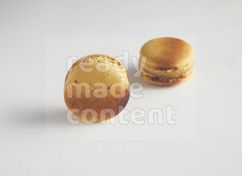 45º Shot of two Yellow Crème Brulée macarons on white background
