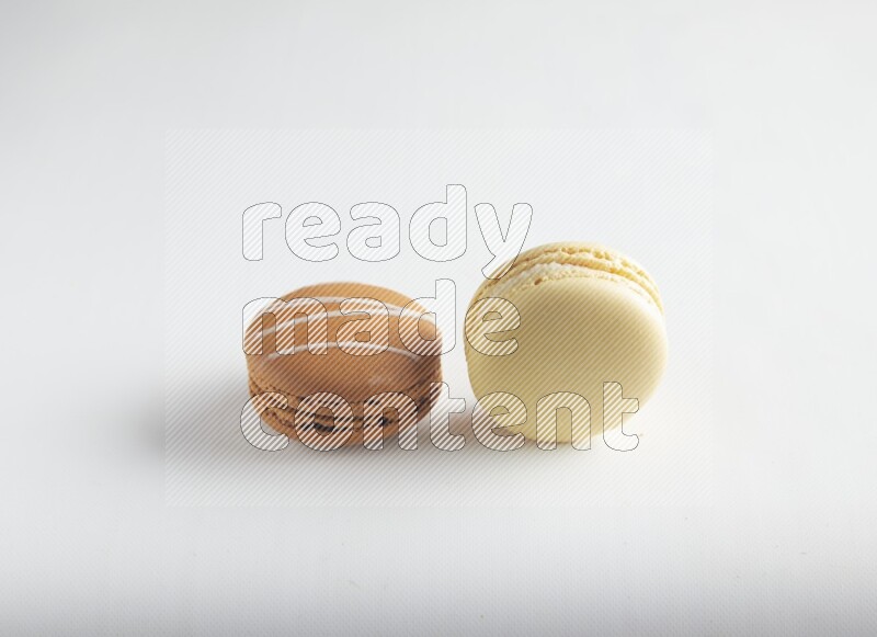 45º Shot of of two assorted Brown Irish Cream, and Yellow Vanilla macarons on white background