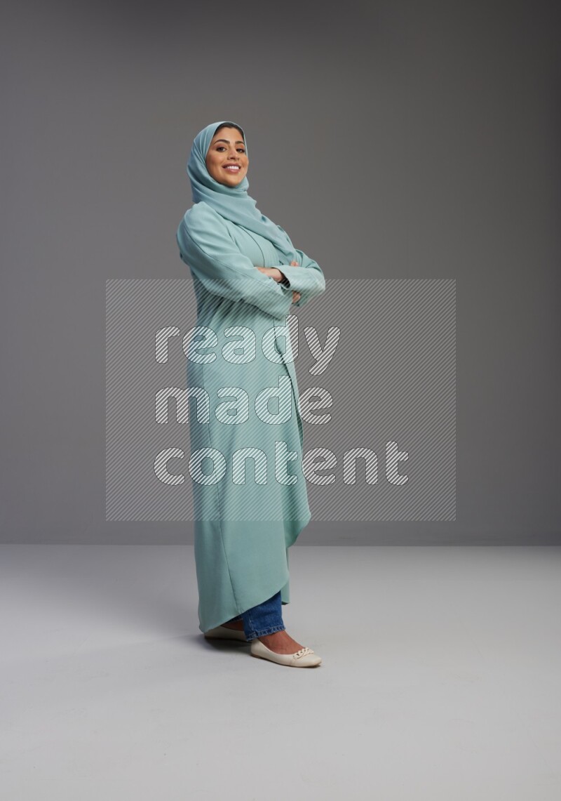 Saudi Woman wearing Abaya standing with crossed arms on Gray background