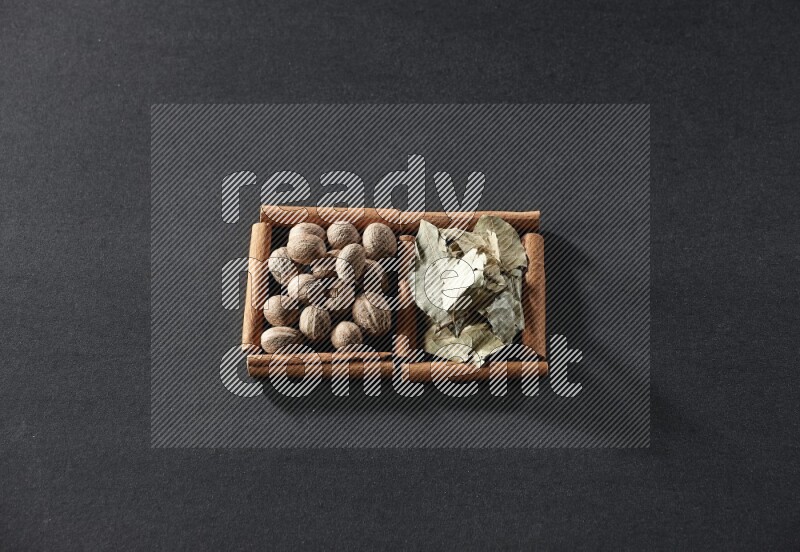 2 squares of cinnamon sticks full of nutmegs and bay laurel leaves on black flooring