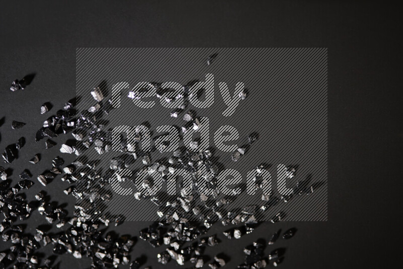 قطع زجاجية سوداء لامعة متناثرة على خلفية سوداء