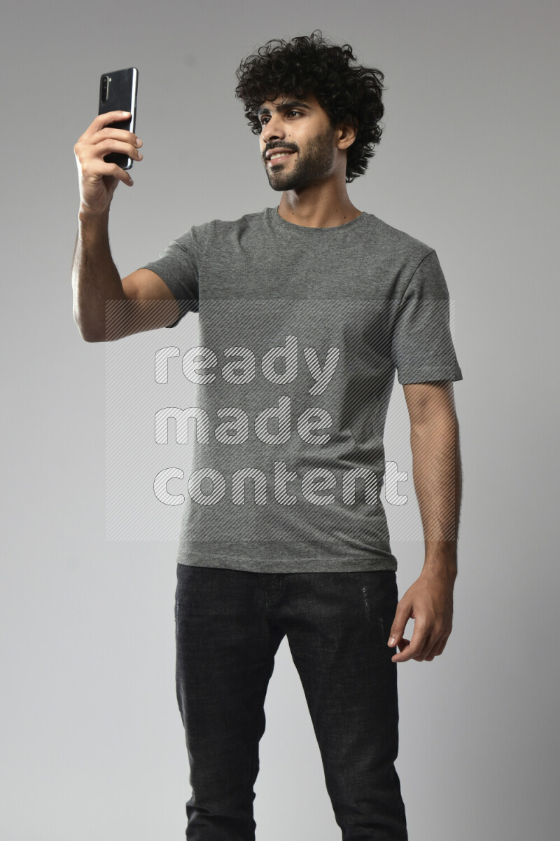 A man wearing casual standing and taking a selfie on white background