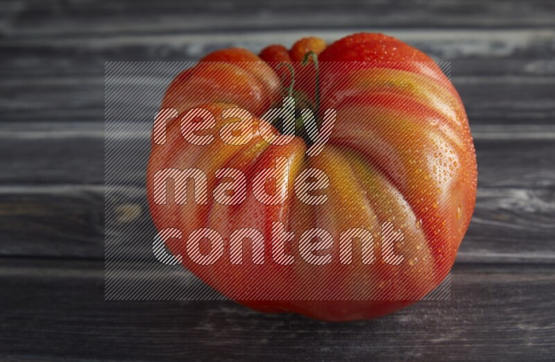 45 degree single heirloom tomato on a textured grey wooden background
