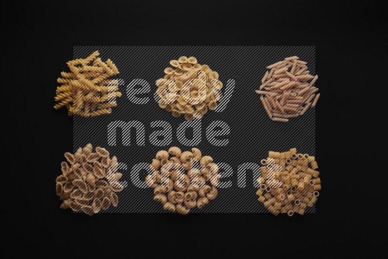 Different pasta types in bunches on black background