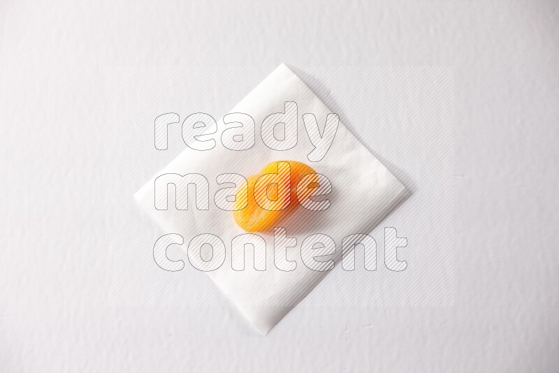 Two dried apricots on a piece of paper on a white background in different angles