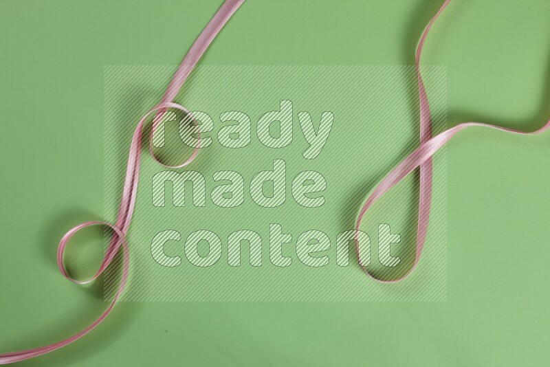 A pink collection of sewing and tailoring tools arranged on a green background