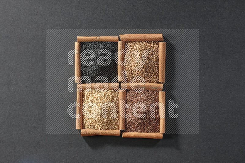 4 squares of cinnamon sticks full of black seeds, sesame, flaxseeds and mustard seeds on black flooring