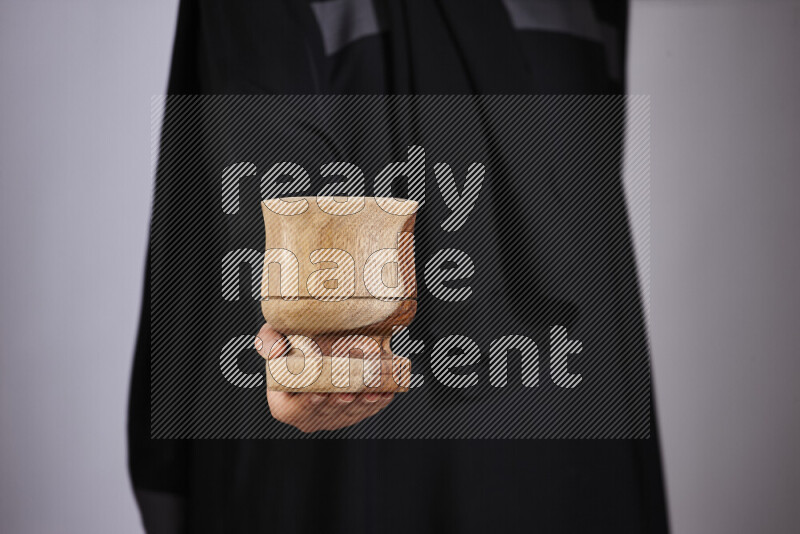 A woman in black abaya holding different wooden essentials in different positions