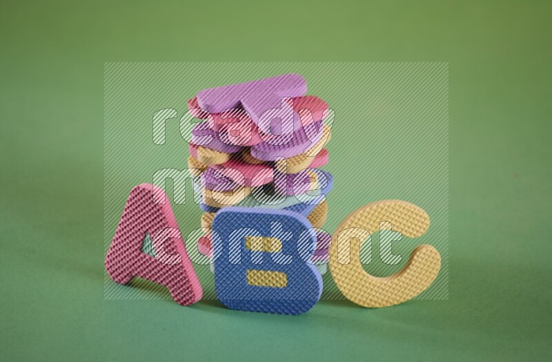 A set of colorful foam alphabet letters on yellow and green background (kids toys)