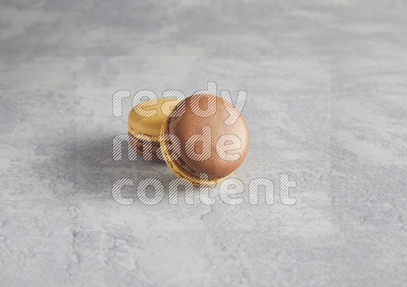 45º Shot of two Yellow and Brown Chai Latte macarons r on white  marble background