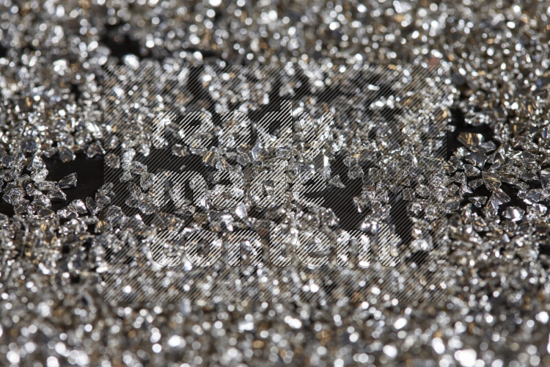 Silver shimmering fragments of glass scattered on a black background