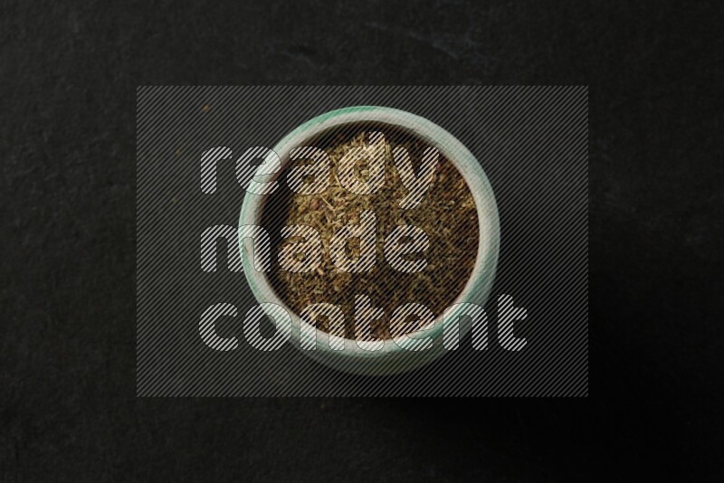 multi color round sauce bowl filled with herbs on grey textured countertop