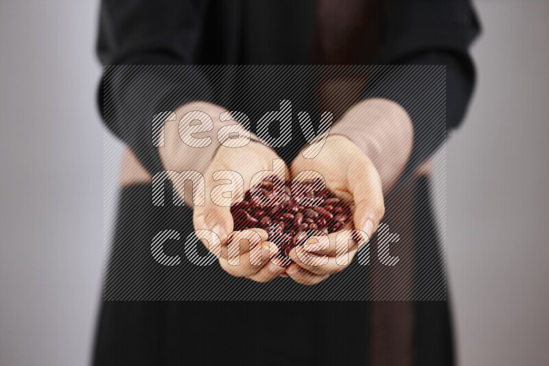 Woman in abaya holding different kinds of legumes in different positions