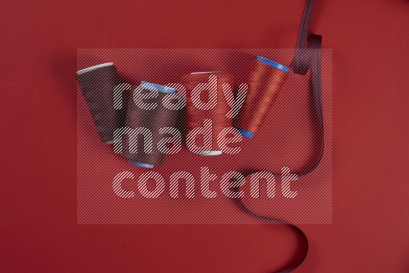 A red collection of sewing and tailoring tools arranged on a red background