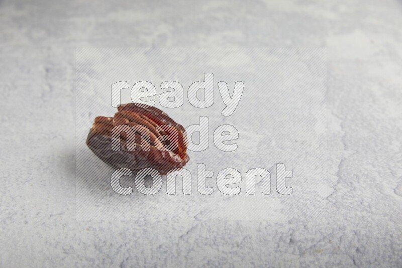 pecan stuffed madjoul date on a light grey background