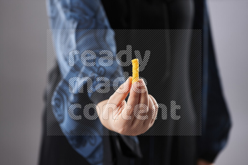 Woman in abaya holding different kinds of snacks in different positions
